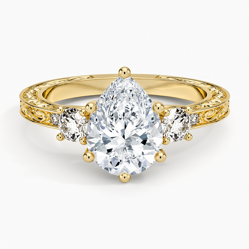 Pear cut moissanite hand engraved scroll three stone engagement ring in yellow gold, top view