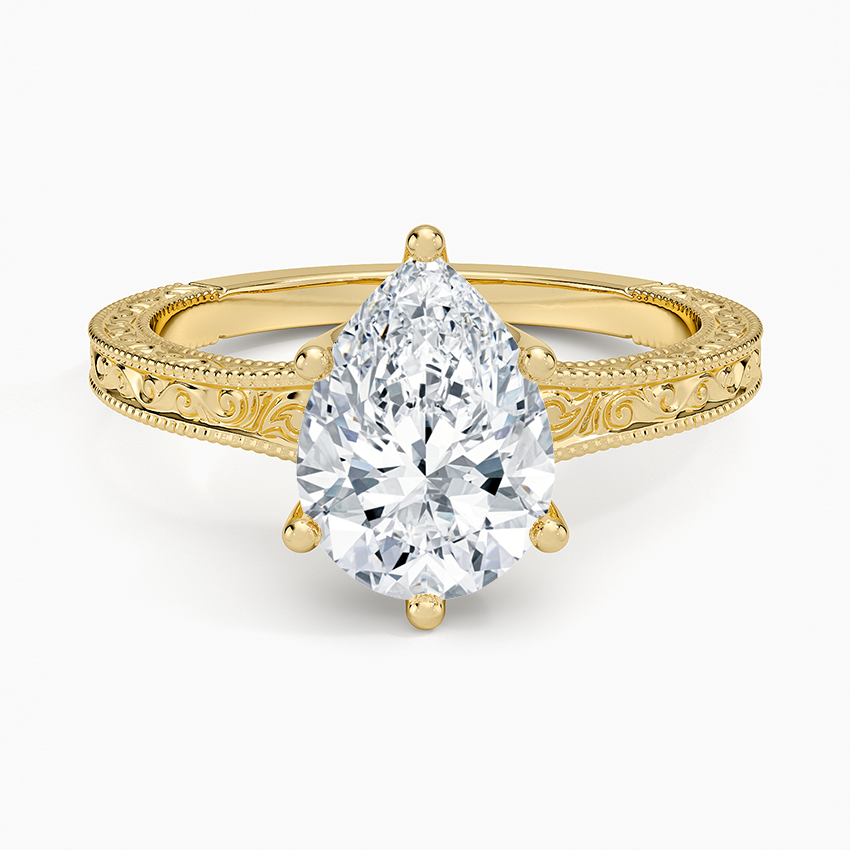 Pear cut moissanite on a flat faced band engraved with a scroll and milgrain edges in yellow gold, top view