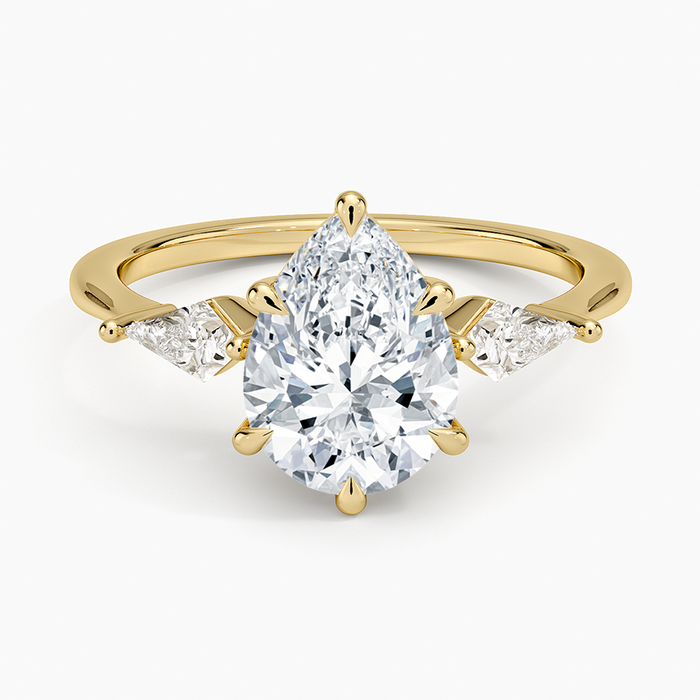 Pear cut moissanite three stone ring with kite cut side stones in yellow gold, top view