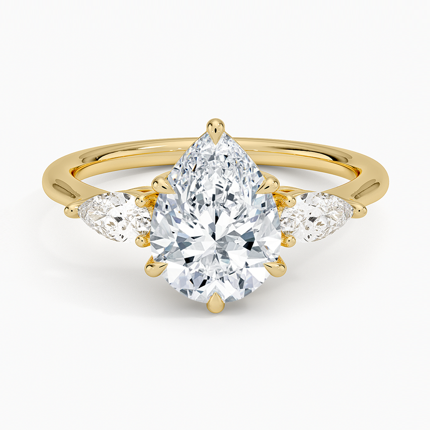 Pear cut moissanite with two small east west pear side stones on a slim band in yellow gold, top view