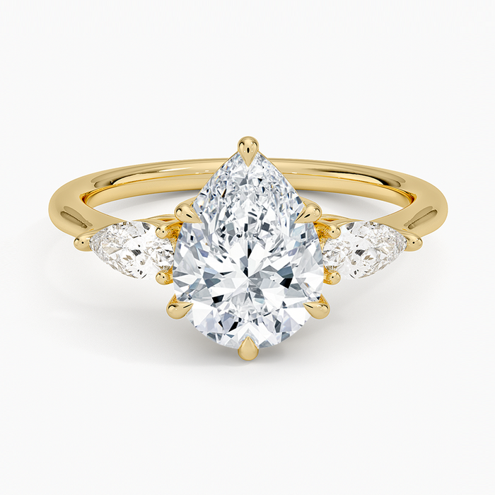 Pear cut moissanite with two small east west pear side stones on a slim band in yellow gold, top view