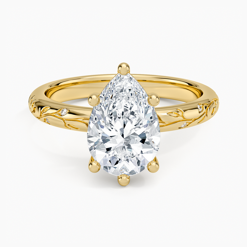 Pear cut moissanite on a slim band with a sculpted vine and leaf shoulders in yellow gold, top view