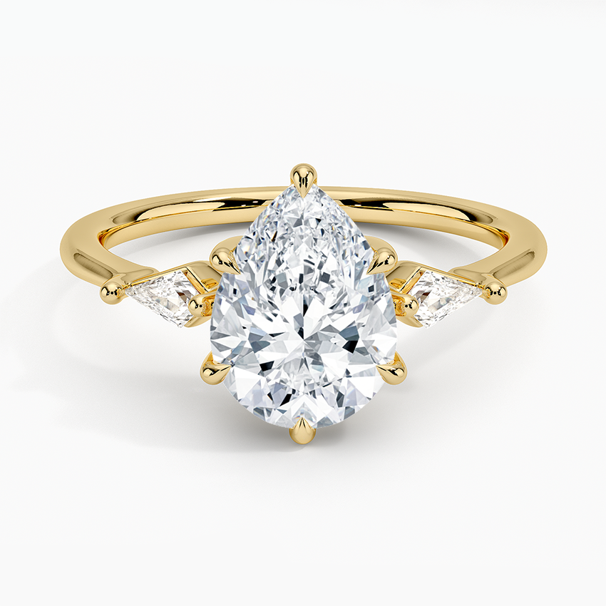 Pear cut moissanite three stone ring with slim kite side stones in yellow gold, top view