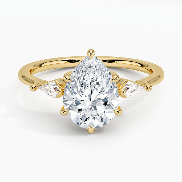 Pear cut moissanite three stone ring with slim kite side stones in yellow gold, top view