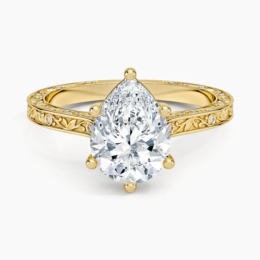 Pear cut moissanite in six claws on a hand engraved leaf and vine band in yellow gold, top view