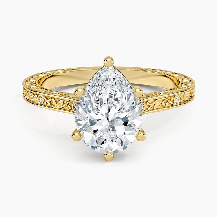Pear cut moissanite in six claws on a hand engraved leaf and vine band in yellow gold, top view