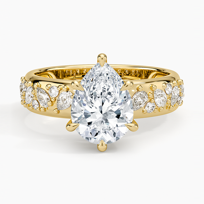 Pear cut moissanite on a wide domed band packed with pear and round accents in yellow gold, top view