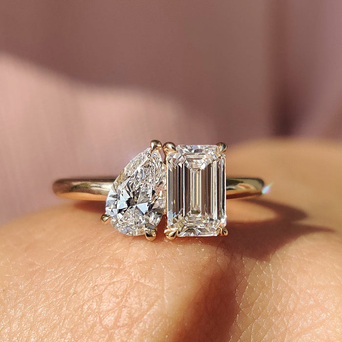 Pear laid east west beside an upright emerald cut moissanite in a toi et moi ring