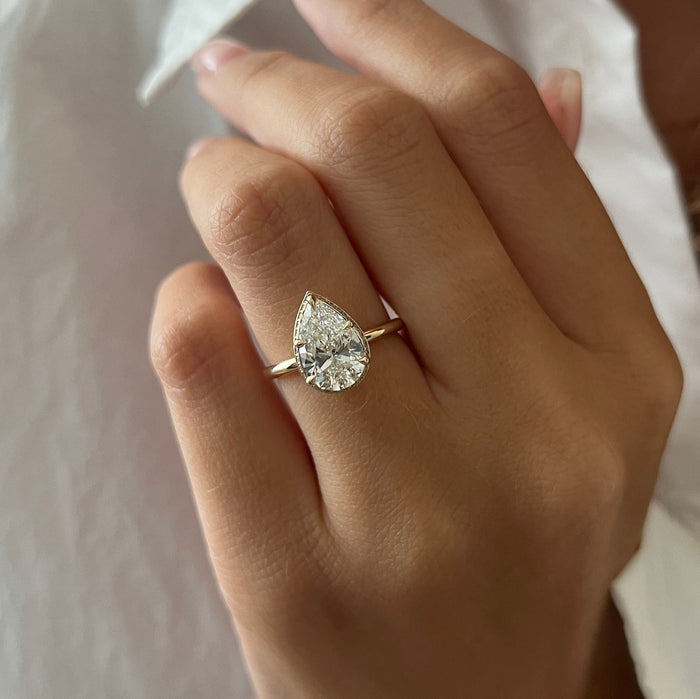 Pear cut moissanite hidden halo engagement ring on a fine band in rose gold