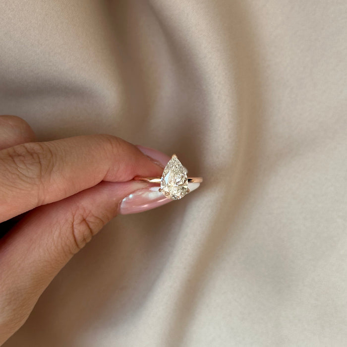 Pear cut moissanite low set solitaire engagement ring on a flat rose gold band, view 2