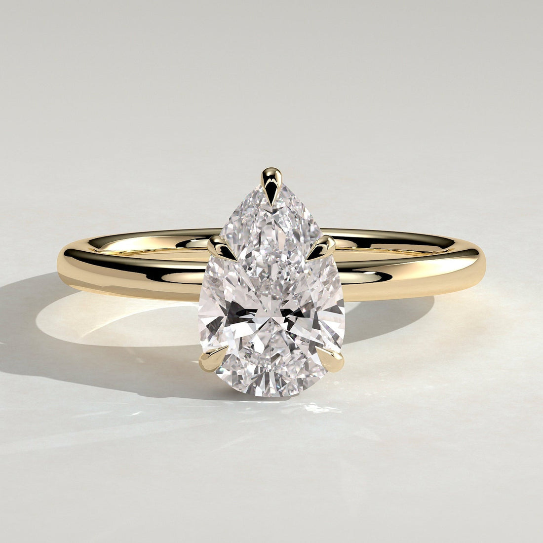 Pear cut moissanite five claw solitaire engagement ring on a plain yellow gold band