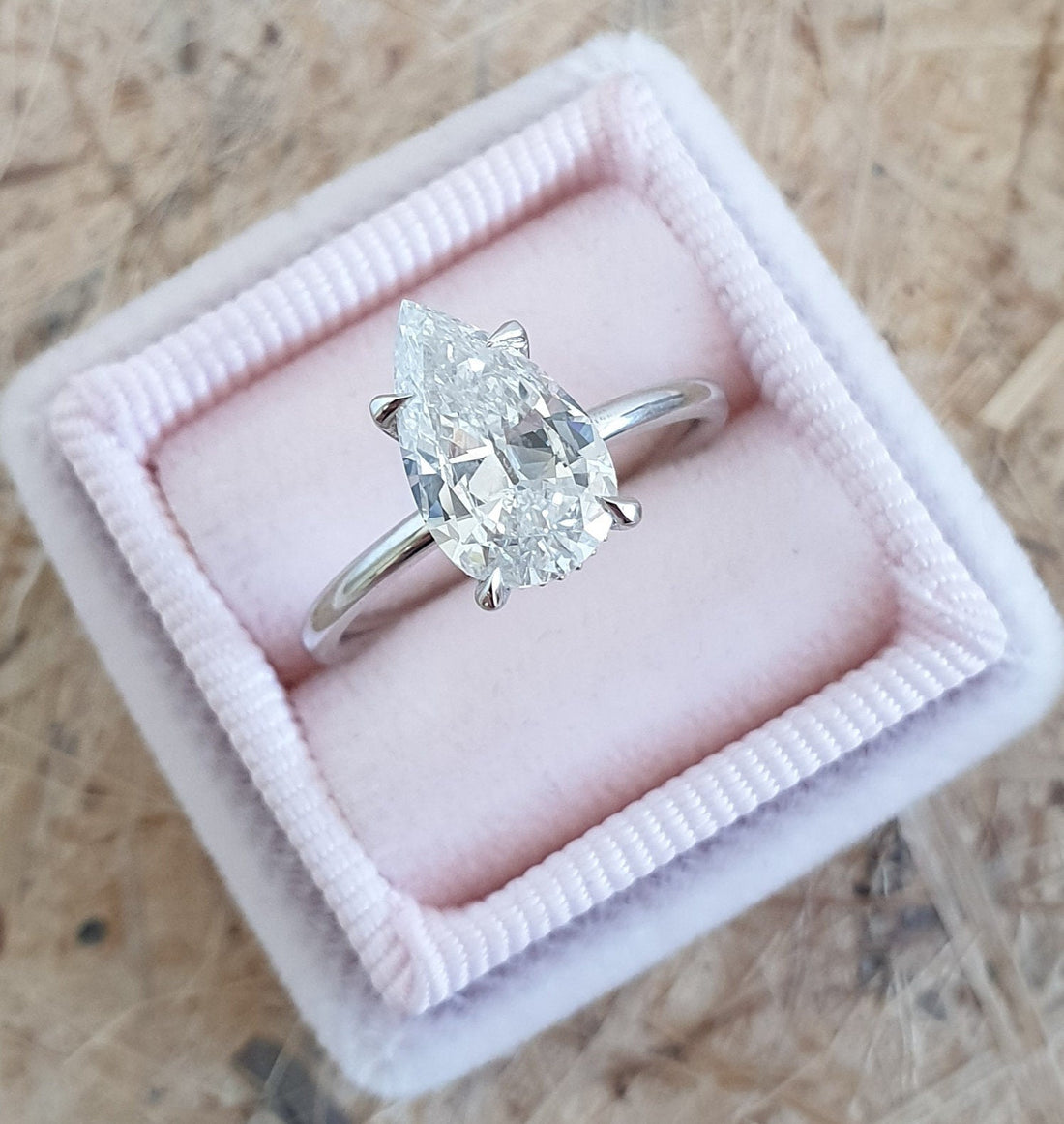 Elongated pear cut moissanite four claw solitaire engagement ring on a rounded white gold band