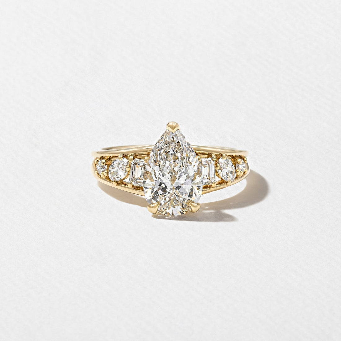 Pear cut moissanite engagement ring with graduated mixed cut shoulders in yellow gold