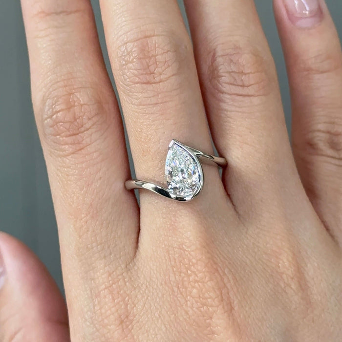 Pear cut moissanite half bezel engagement ring on a bypass shank in white gold