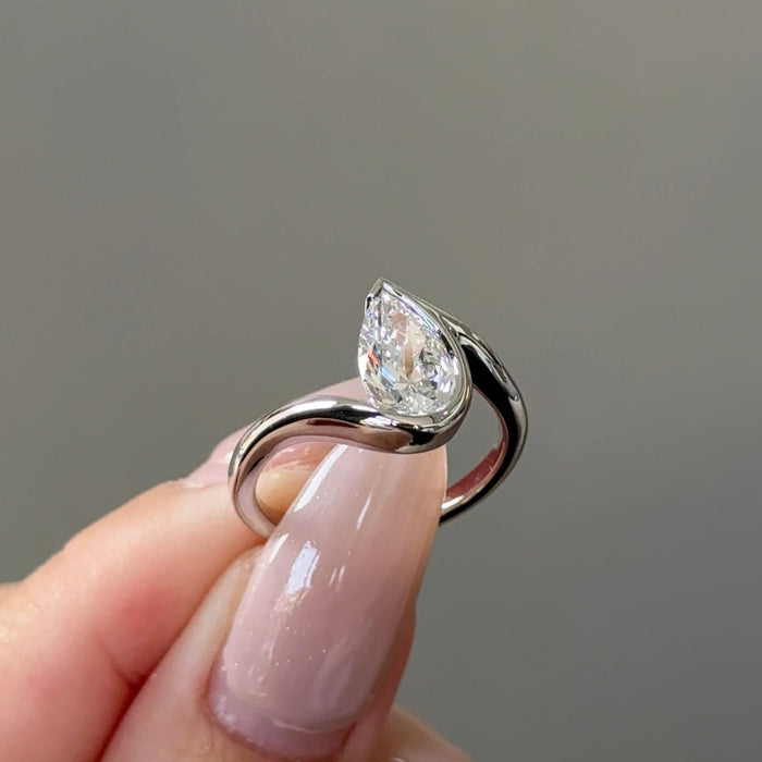 Pear cut moissanite half bezel engagement ring on a bypass shank in white gold, view 2