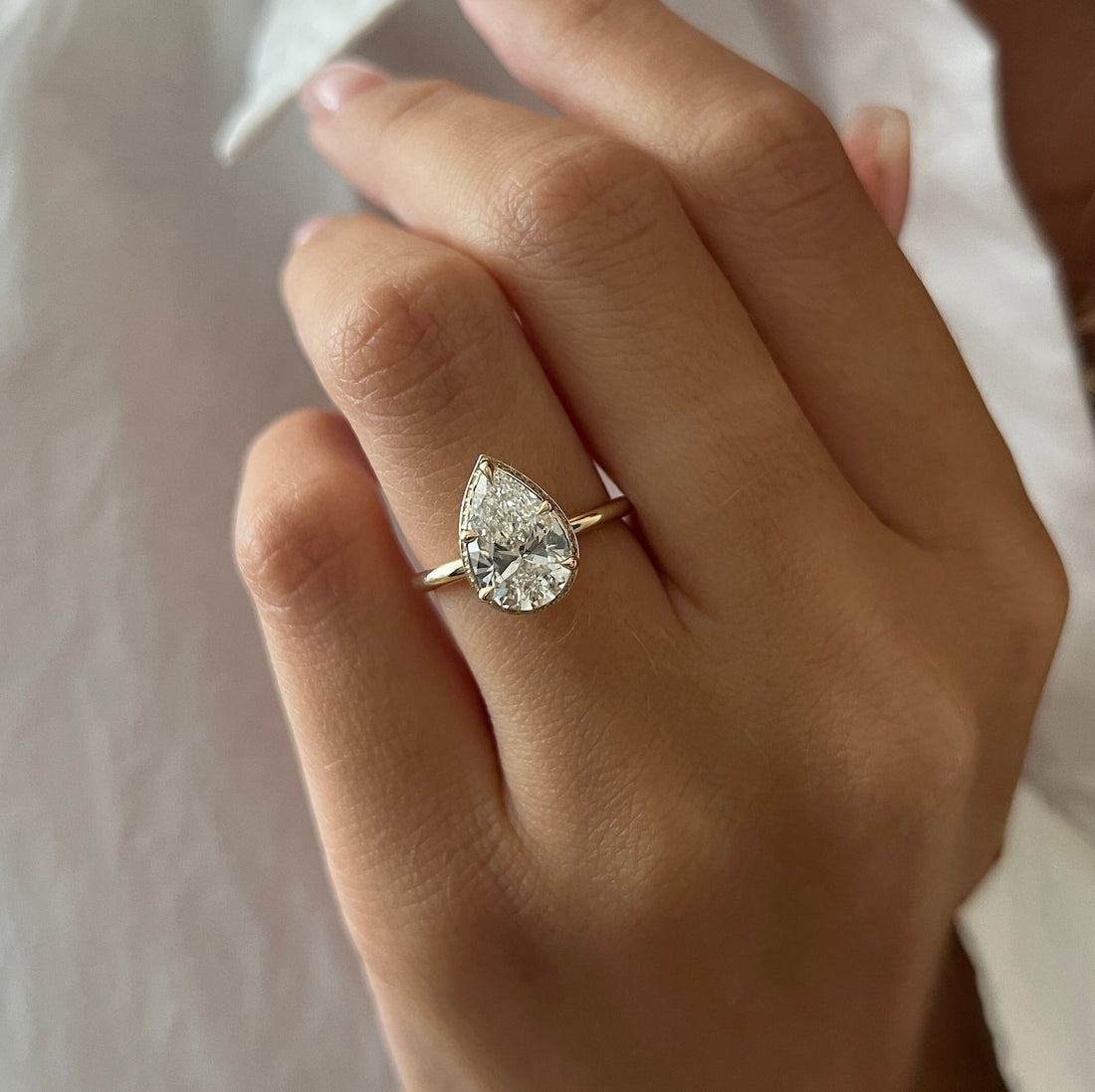 Pear cut moissanite hidden halo engagement ring in rose gold