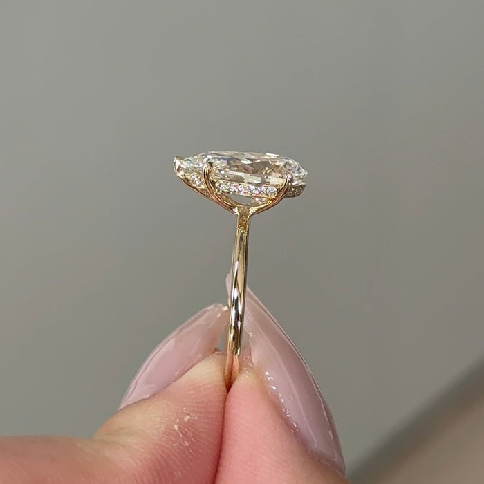 Pear cut moissanite hidden halo engagement ring on a knife edge yellow gold band, view 2