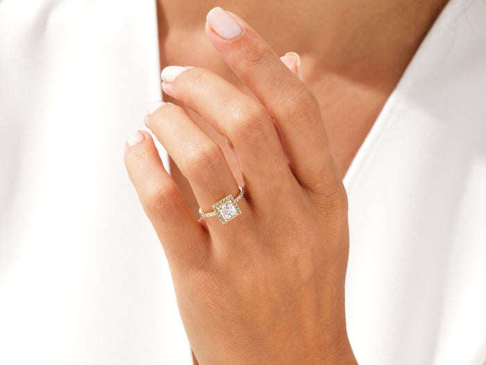 Princess cut moissanite halo ring in yellow gold worn on the hand