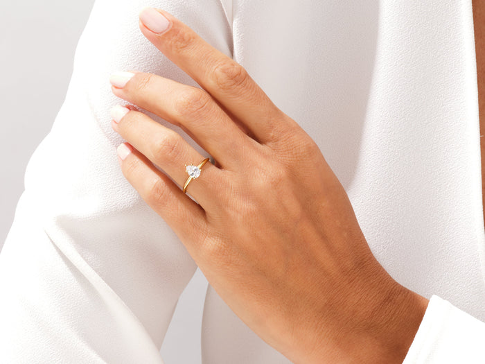 Teardrop pear cut lab grown diamond solitaire in yellow gold worn on the hand near the shoulder