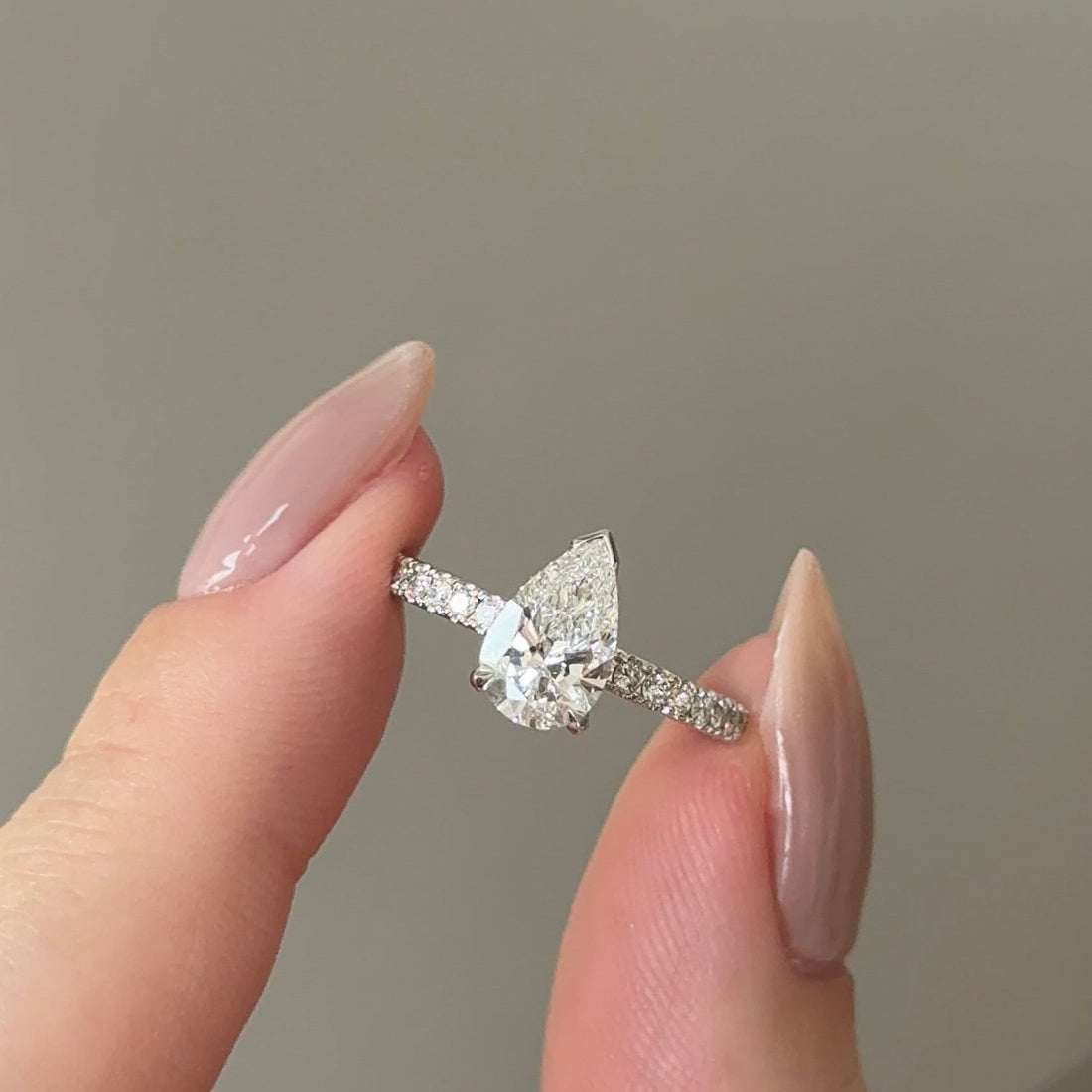 Pear cut moissanite solitaire engagement ring on a pave set white gold band