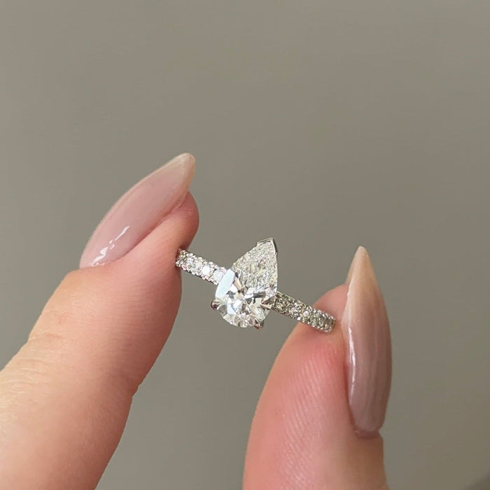Pear cut moissanite solitaire engagement ring on a pave set white gold band