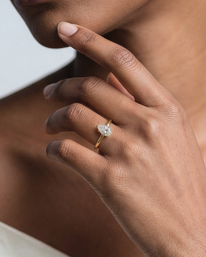 Pear cut lab grown diamond solitaire in yellow gold worn on the hand at the jaw