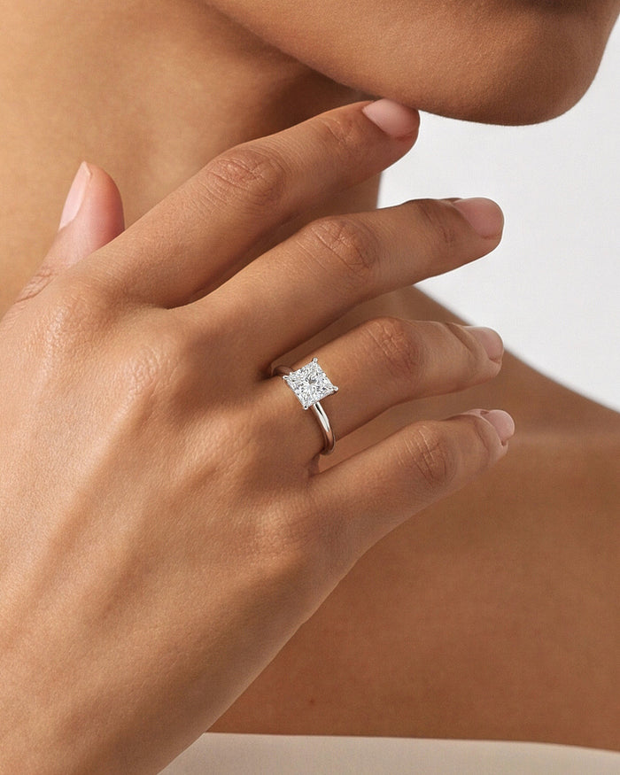 Princess cut lab grown diamond V prong solitaire in white gold worn on the hand at the chin