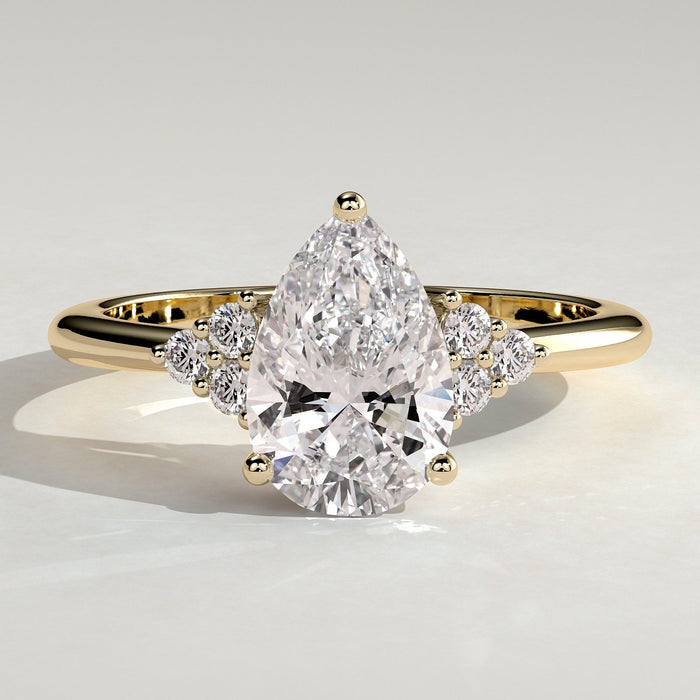 Pear cut moissanite engagement ring with triangular cluster shoulders in yellow gold