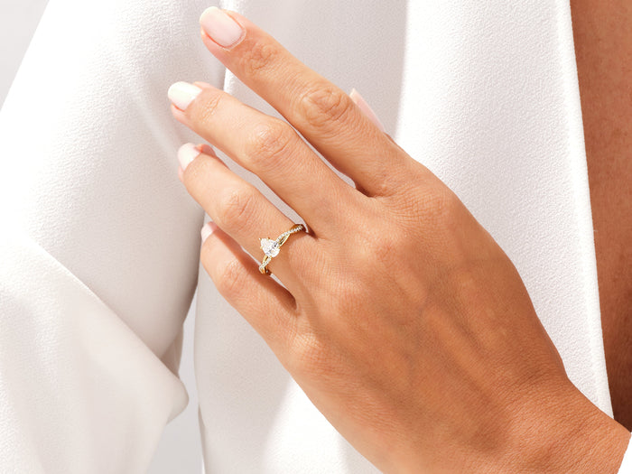 Pear cut lab grown diamond braided engagement ring in yellow gold worn on the hand at the lapel