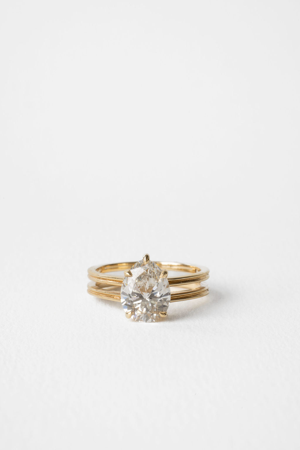 Pear cut moissanite triple rail shank solitaire engagement ring in yellow gold