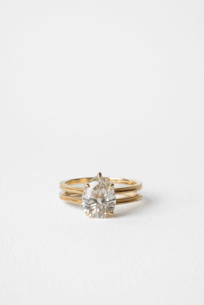 Pear cut moissanite triple rail shank solitaire engagement ring in yellow gold