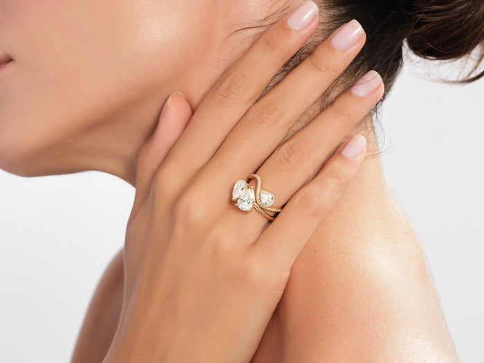 Pear lab grown diamond wave band ring in yellow gold worn on the hand at the neck
