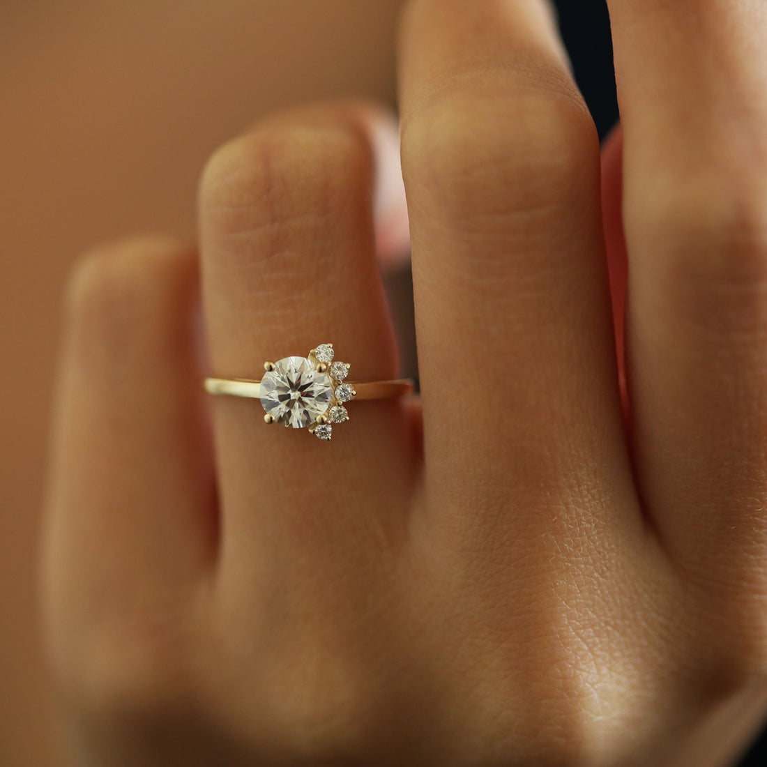 Round brilliant moissanite with an asymmetric crescent of accents on a hairline yellow gold band