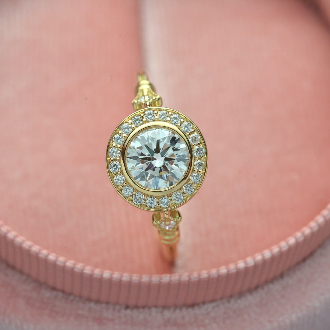 Round brilliant moissanite bezel set inside a pave target halo in yellow gold