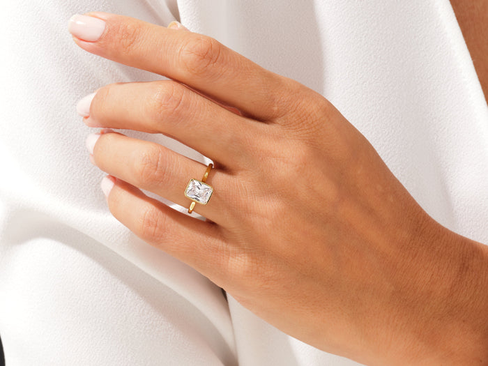 Rectangle radiant moissanite bezel ring in yellow gold worn on the ring finger