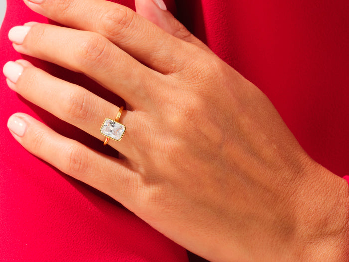 Radiant moissanite bezel engagement ring in yellow gold worn on the hand