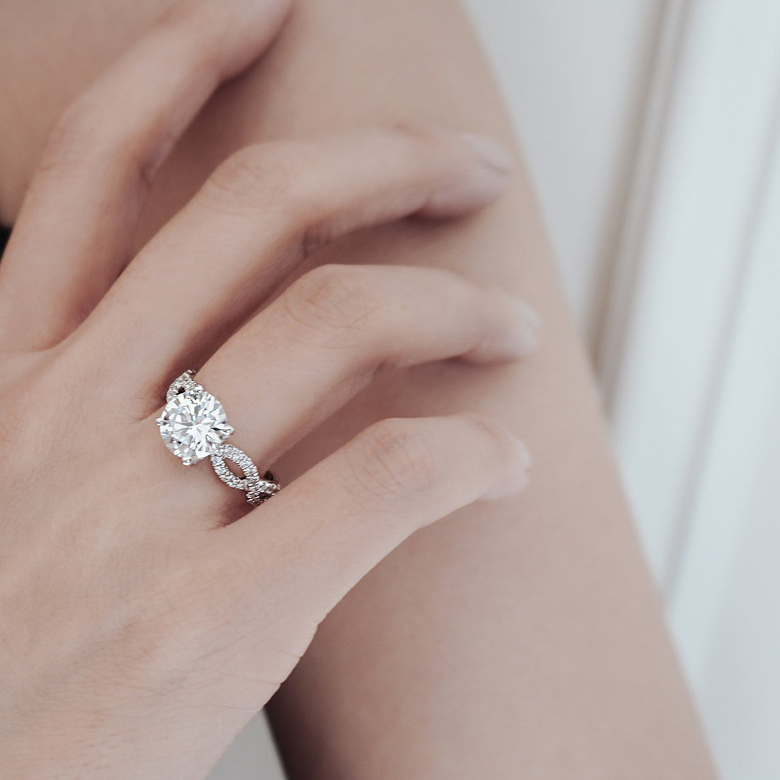 Round brilliant moissanite engagement ring on a criss cross pave braided shank in white gold