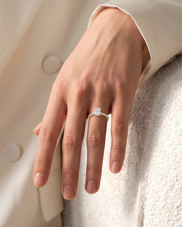 Radiant cut lab grown diamond pave engagement ring in white gold worn on the hand against a cream knit