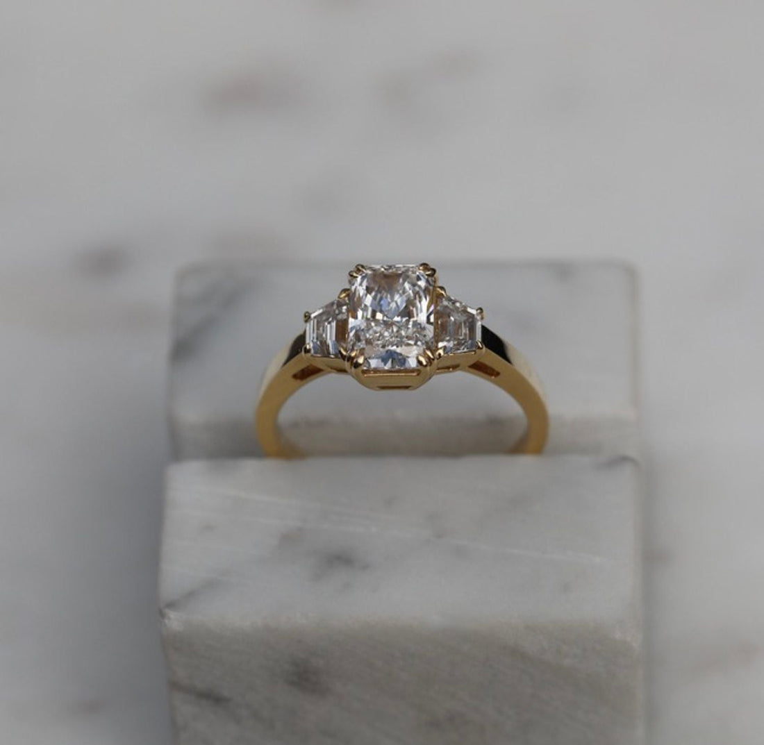 Radiant cut moissanite three stone engagement ring with trapezoid sides in yellow gold
