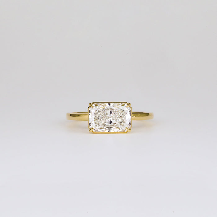 East west radiant cut moissanite half bezel solitaire engagement ring in yellow gold
