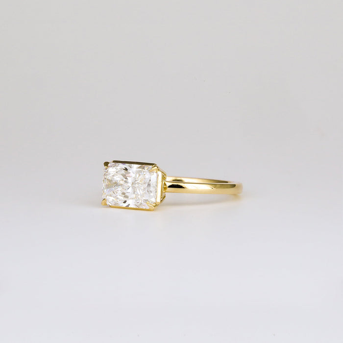 East west radiant cut moissanite half bezel solitaire engagement ring in yellow gold, view 2