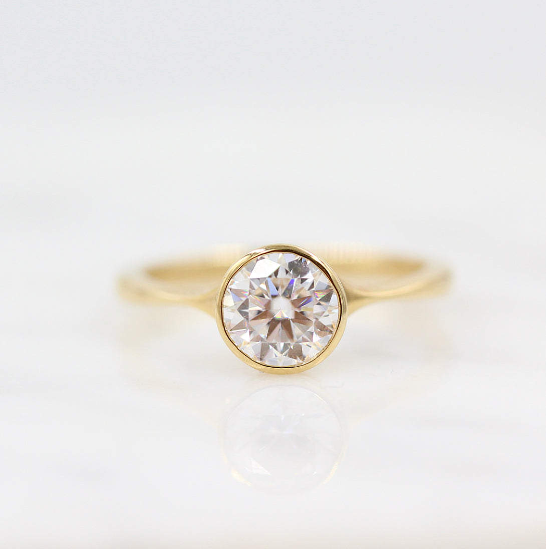 Round brilliant moissanite full bezel solitaire engagement ring on a plain yellow gold band