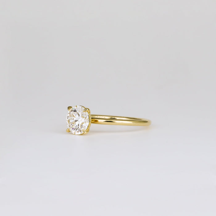 Round brilliant moissanite four claw solitaire engagement ring on a plain yellow gold band, view 2