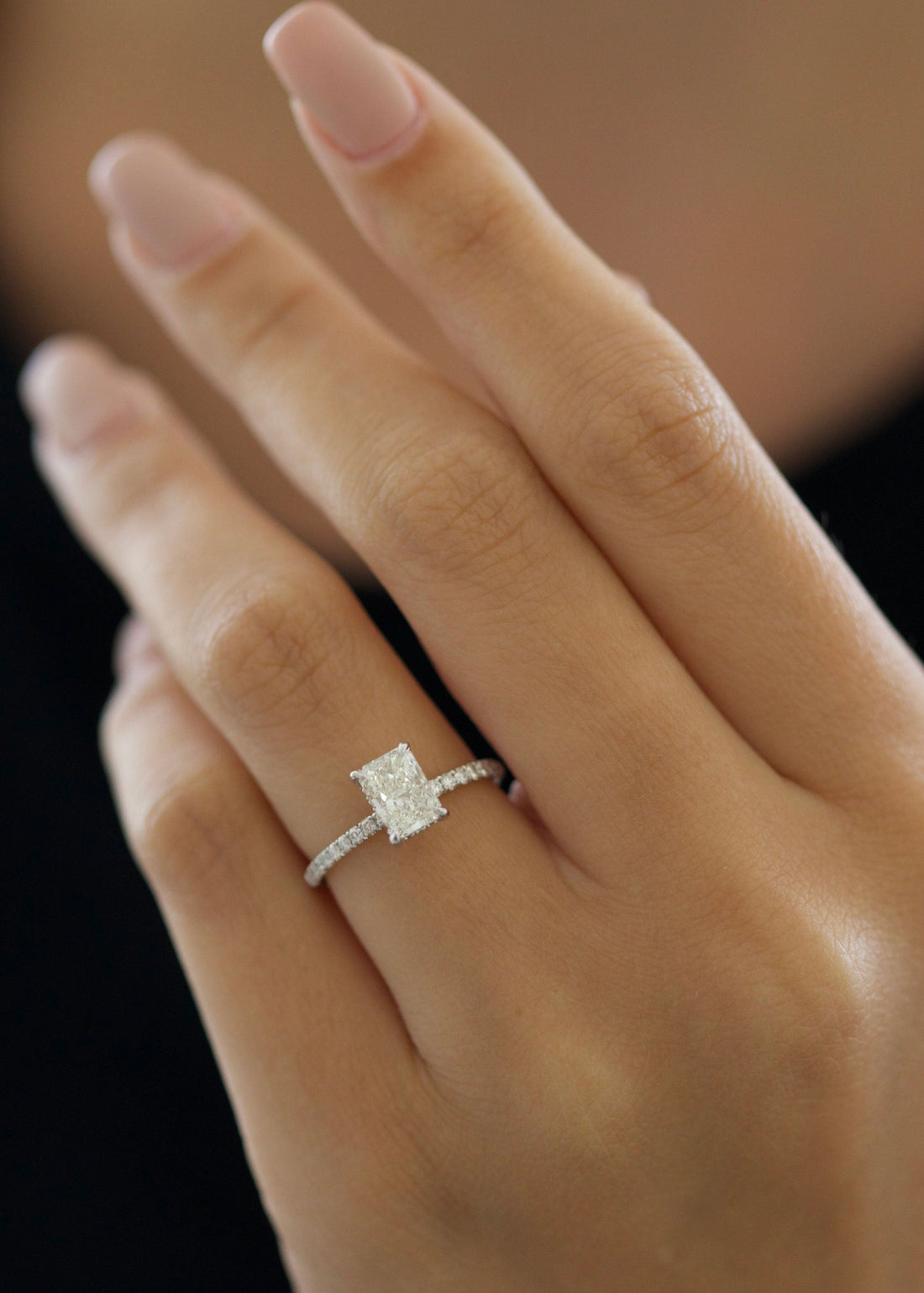 Radiant cut moissanite solitaire engagement ring on a fine pave white gold band