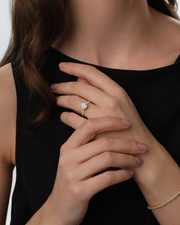 Round lab grown diamond half pave ring in yellow gold worn on the hand against a black top