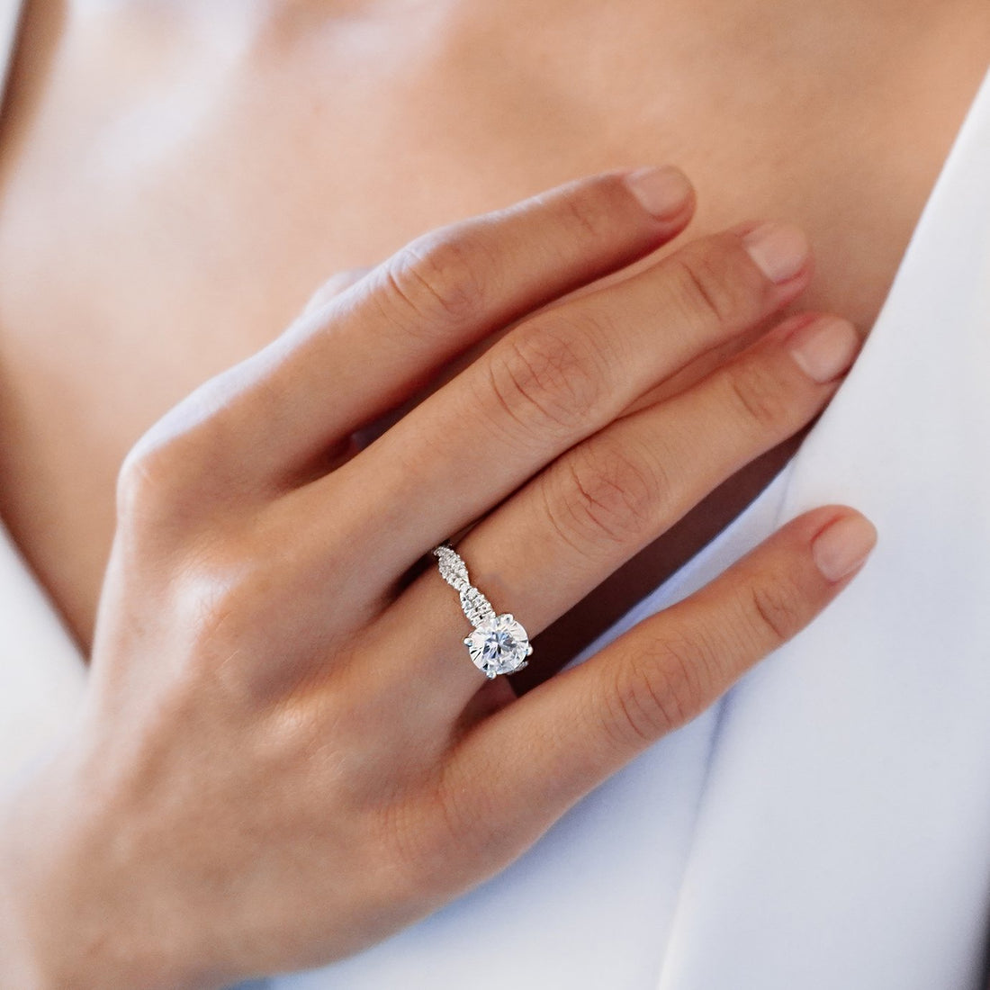 Round brilliant moissanite four claw engagement ring on a graduated pave shank in white gold