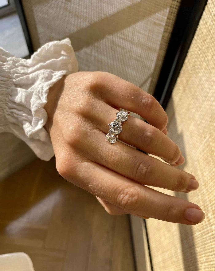 Round cut moissanite graduated three stone trilogy engagement ring in yellow gold