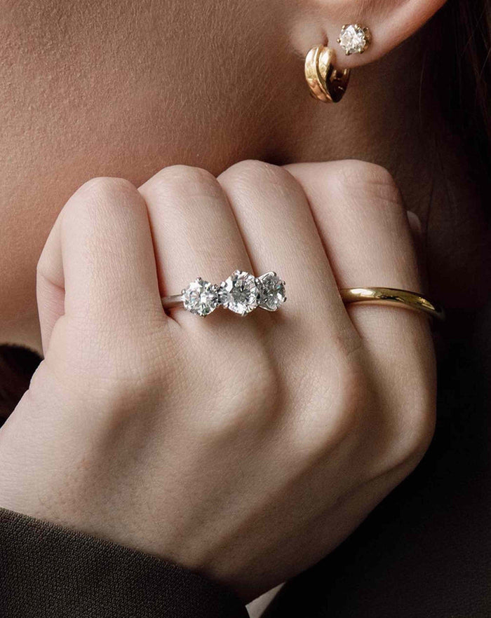 Round cut moissanite graduated three stone trilogy engagement ring in yellow gold, view 2