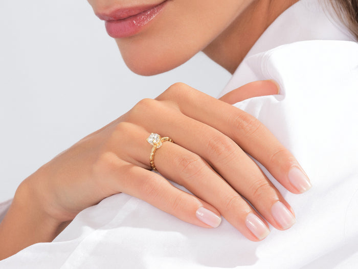 Round lab grown diamond hidden halo ring in yellow gold worn on the hand resting on the shoulder