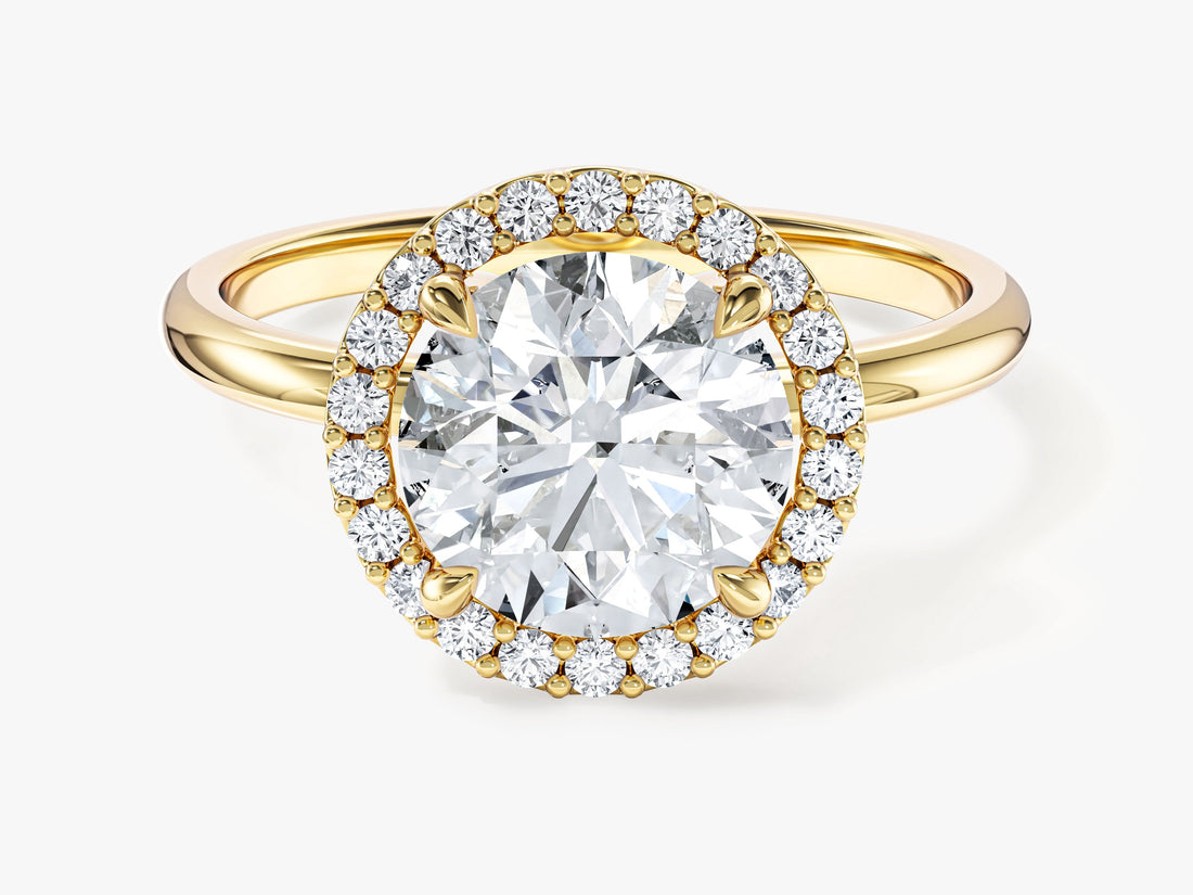 Round brilliant moissanite four claw halo engagement ring on a slim band in yellow gold, front view